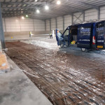Workers pouring concrete onto the floor of warehouse, Cookstown